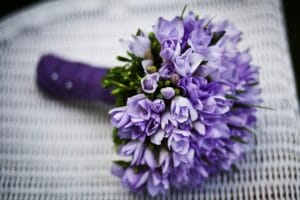 A bouquet of purple flowers sits on a white chair.